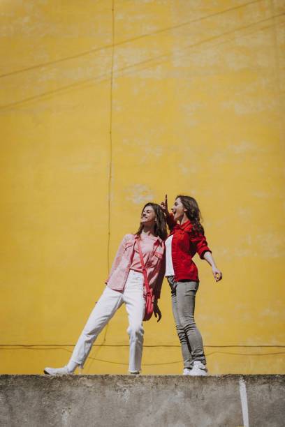 istock Two happy hipster girls staying on parapet 1151404968