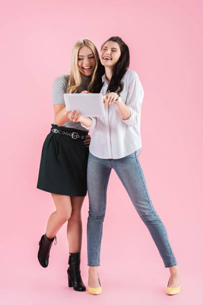istock Excited young women using digital tablet on pink background 1151410261