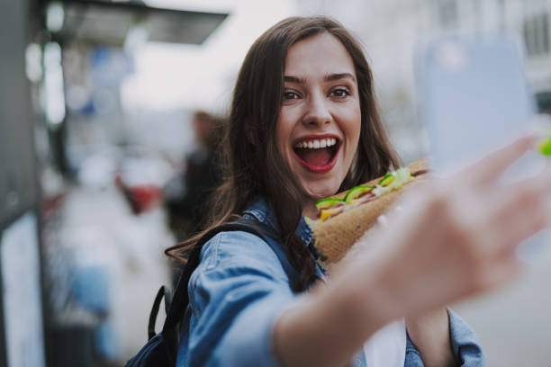 femme heureuse faisant le selfie avec la nourriture rapide - people eating walking fun photos et images de collection