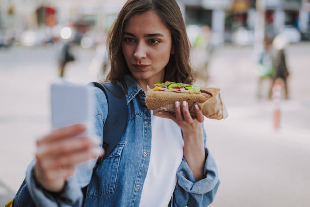 istock Pretty female making funny selfie with hot dog 1151411399