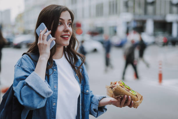 istock Charming female talking by phone with fast food 1151411411
