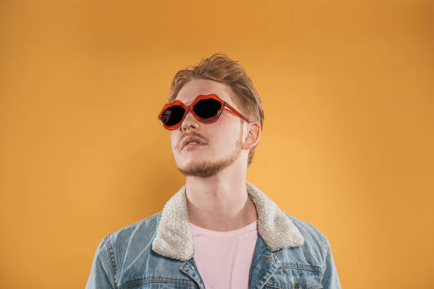 istock Young man in lip shaped sunglasses on yellow background 1151417464
