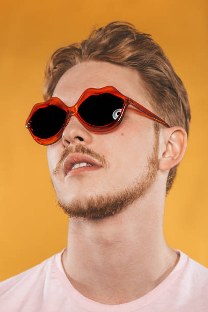 istock Young man in lip shaped sunglasses on yellow background 1151417485