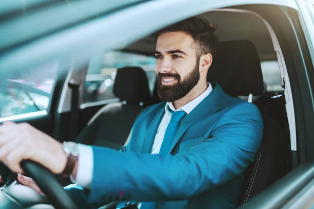 młody atrakcyjny zamożny kaukaski biznesmen w niebieskim garniturze jazdy swoim samochodem. - people behavior smiling mode of transport zdjęcia i obrazy z banku zdjęć