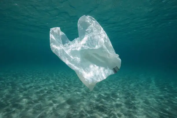 Plastic waste underwater, a plastic bag in the Mediterranean sea between water surface and a sandy seabed, Almeria, Andalusia, Spain