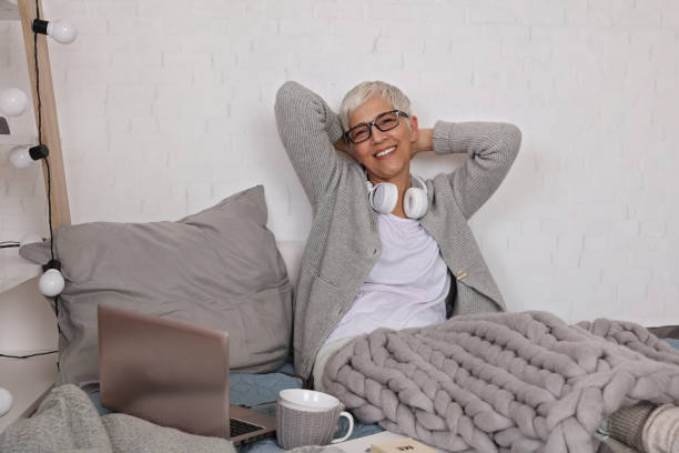 Cozy and comfy, Woman covered with soft woolen blanket, relaxing at home,drinking cacao, listening music.