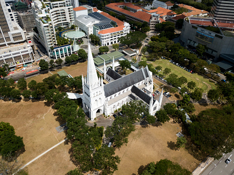 Gothic Church in Singapore from drone. Scenic aerial view. High buildings, skyscrapers, green trees around the church.