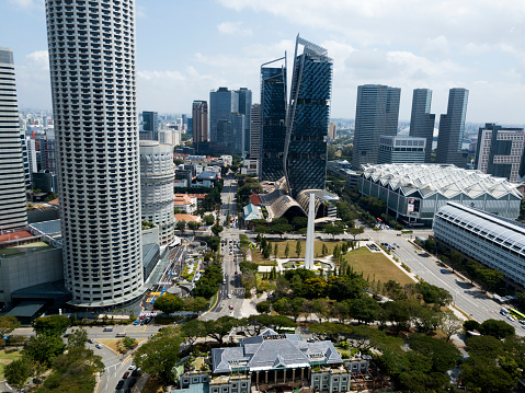 Singapore from drone. Glass high-rises, skyscrapers, high buildings near river, green trees, road with cars. Futuristic city.
