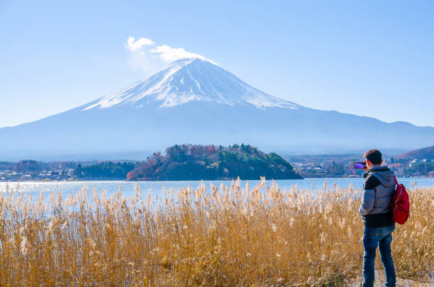 homme de photographe restant la photographie extérieure par mobile au milieu de la belle nature du mont fuji à yamanashi au japon avec le lac kawaguchiko. concept de voyage et d'attractions. - lake kawaguchi photos et images de collection