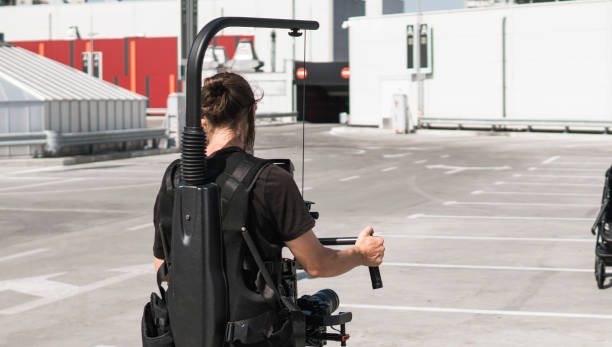 istock Professional videographer holding camera on 3-axis gimbal which mounted on easy rig. Videographer using steadicam. Pro equipment helps to make high quality video without shaking. 1151424055