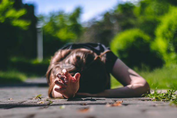 Person lying on the ground with one hand reaching for help stock photo