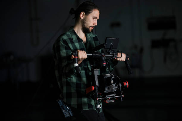 istock Professional videographer holding camera on 3-axis gimbal. Videographer using steadicam. Pro equipment helps to make high quality video without shaking. 1151427329