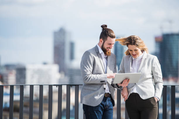 istock Two young business people with tablet standing on a terrace outside office, working. 1151427966
