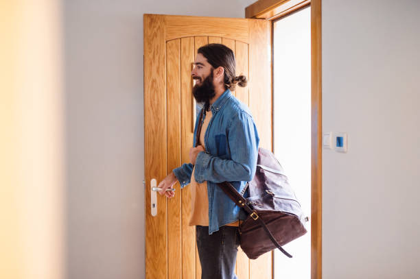 istock Young hipster man with bag entering front door when coming back home. 1151428009