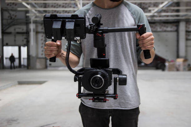 istock Professional videographer holding camera on 3-axis gimbal. Videographer using steadicam. Pro equipment helps to make high quality video without shaking. 1151428091