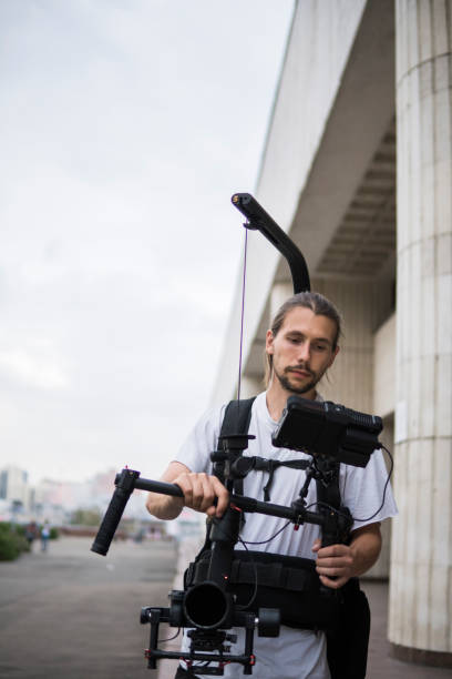 istock Professional videographer holding camera on 3-axis gimbal which mounted on easy rig. Videographer using steadicam. Pro equipment helps to make high quality video without shaking. 1151428343