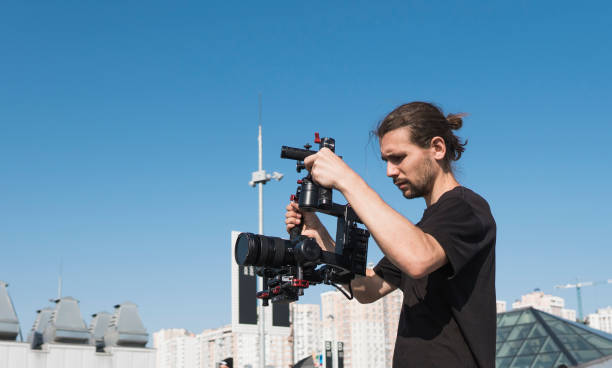 istock Professional videographer holding camera on 3-axis gimbal. Videographer using steadicam. Pro equipment helps to make high quality video without shaking. 1151429185