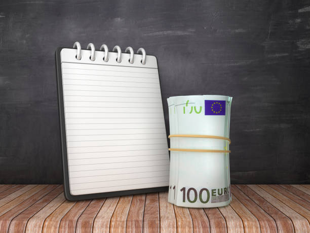 istock Note Pad with Euro Money Roll on Chalkboard Background - 3D Rendering 1151432340