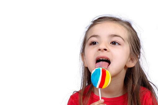 Portrait of little girl eating a colorful lollipop on studio.