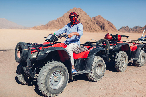 Senior man driving quad bike in Sinai desert. Happy tourist having fun during summer vacationin Egypt