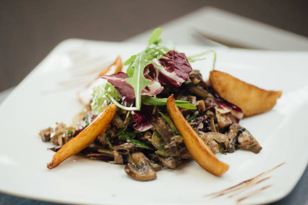 istock Salad with fried mushrooms, fried potatoes, greens on a plate on the table 1151437171
