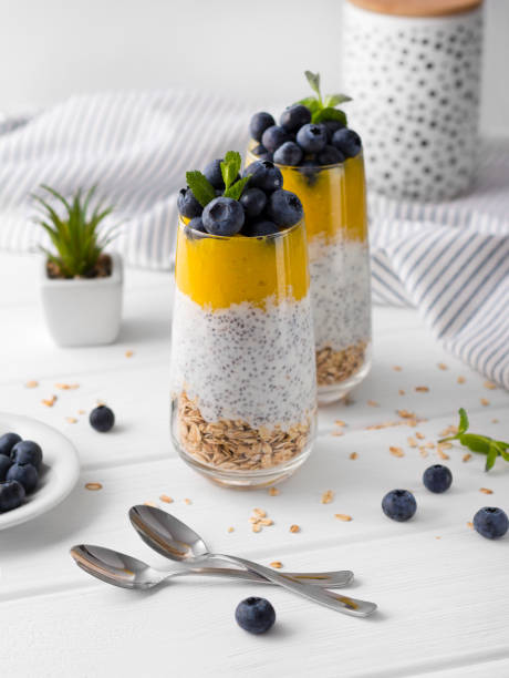 istock Two Glasses of chia pudding with blueberries, mango mousse and oat granola on the kitchen table. 1151438858