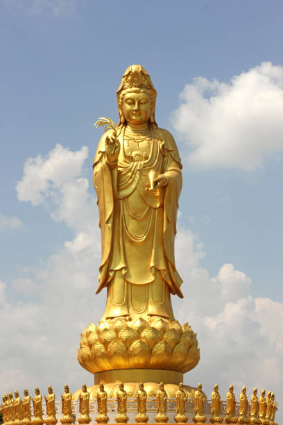 Golden Guanyin statue on a clear sky background.