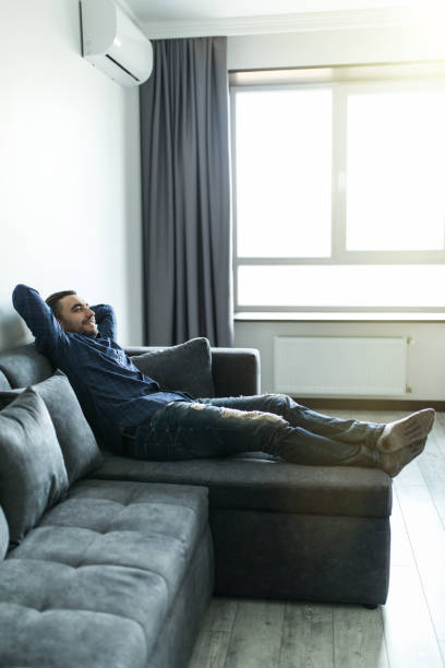 istock Time to relax. Handsome young man holding hands behind head while sleeping on the couch 1151447499