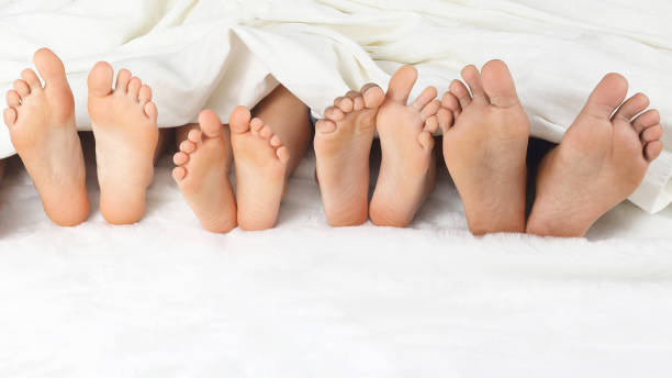 istock many children's feet peeking from under the blanket 1151455971