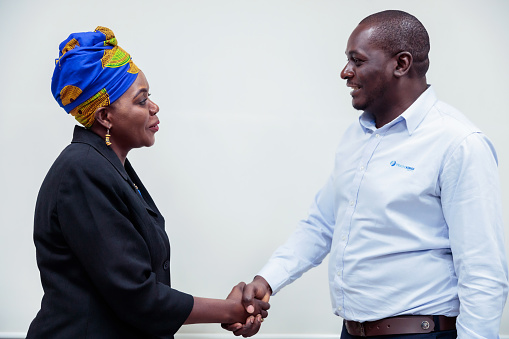 Handshake of two businessmen on the background of empty modern office, partnership concept, close up