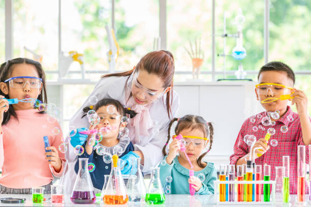 istock Teacher and students blowing bubbles in lab. 1151467436