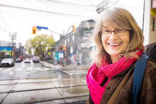 Beautiful vibrant smiling mature woman portrait in downtown Toronto streetcar on a rainy day