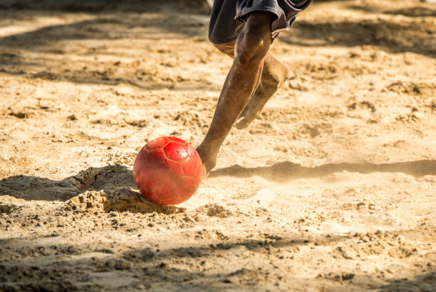 Beach soccer leg closeup and ball with soft sand speed cloud