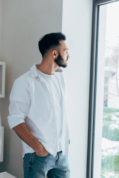 istock Pensive man standing with hand in pocket and looking at window 1151479721
