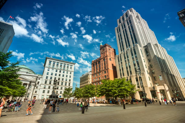 Place d'Armes plaza in historic Old Montreal, Quebec Montreal, Quebec, Canada - August 23, 2018:  People walk along the historic cobblestone Place d'Armes plaza in Old Montreal, Quebec, Canada.  Old Montreal (French: Vieux-Montréal) is the oldest area in the city of Montreal, Quebec, Canada, with a few remains dating back to New France. place darmes montreal stock pictures, royalty-free photos & images