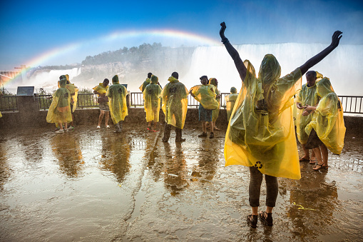 Niagara Falls, Ontario, Canada - September 5, 2018:  Tourists wear rain protection poncho coats to stay dry in the wet spray mist from the river flowing over the Niagara Falls.  Niagara Falls is the collective name for three waterfalls that straddle the international border between Canada and the United States.