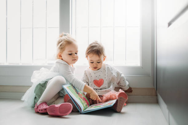 istock Sisters reading a book together in a window seat 1151484584