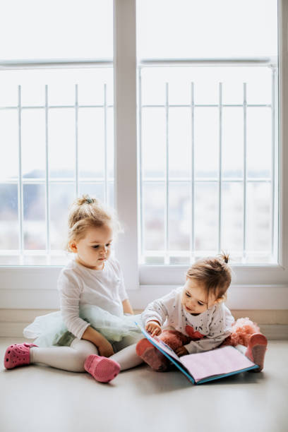istock Sisters reading a book together in a window seat 1151484709