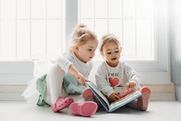 istock Sisters reading a book together in a window seat 1151484778