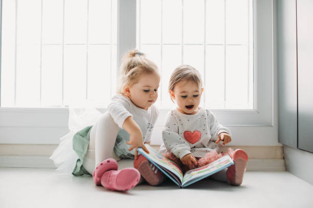 istock Sisters reading a book together in a window seat 1151484809