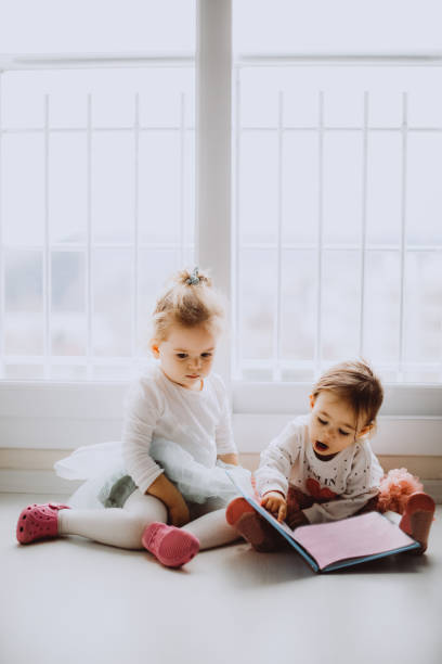 istock Sisters reading a book together in a window seat 1151484830