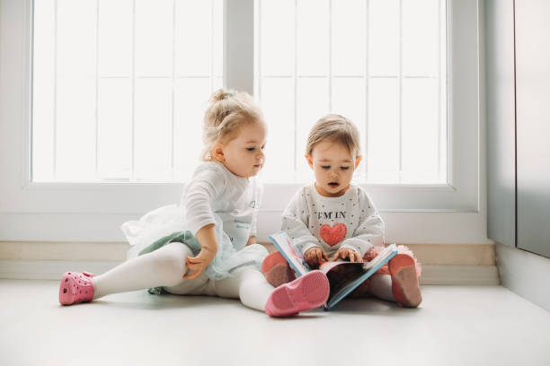 istock Sisters reading a book together in a window seat 1151485424