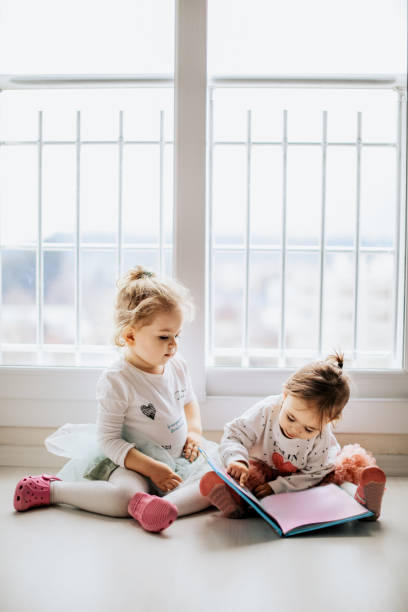 istock Sisters reading a book together in a window seat 1151485470