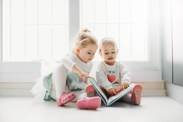istock Sisters reading a book together in a window seat 1151485481