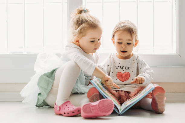 istock Sisters reading a book together in a window seat 1151485504