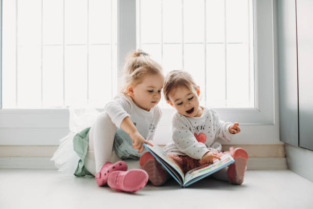 istock Sisters reading a book together in a window seat 1151485645