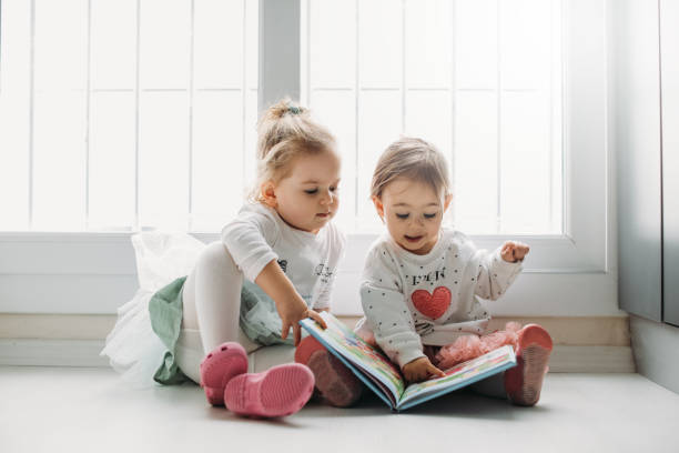 istock Sisters reading a book together in a window seat 1151485682