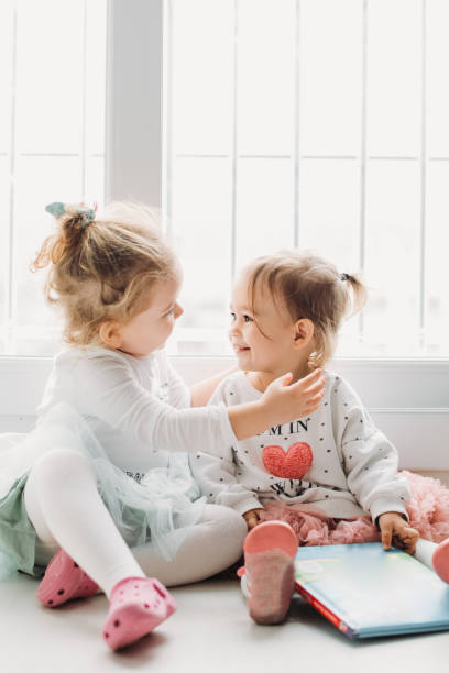 istock Sisters reading a book together in a window seat 1151485711