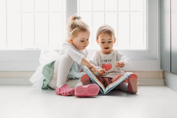 istock Sisters reading a book together in a window seat 1151485757