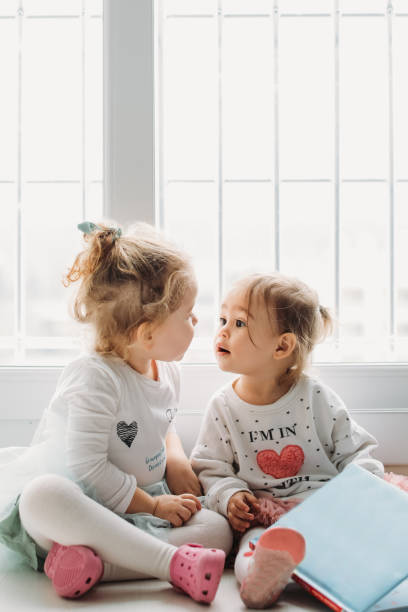 istock Sisters reading a book together in a window seat 1151486452